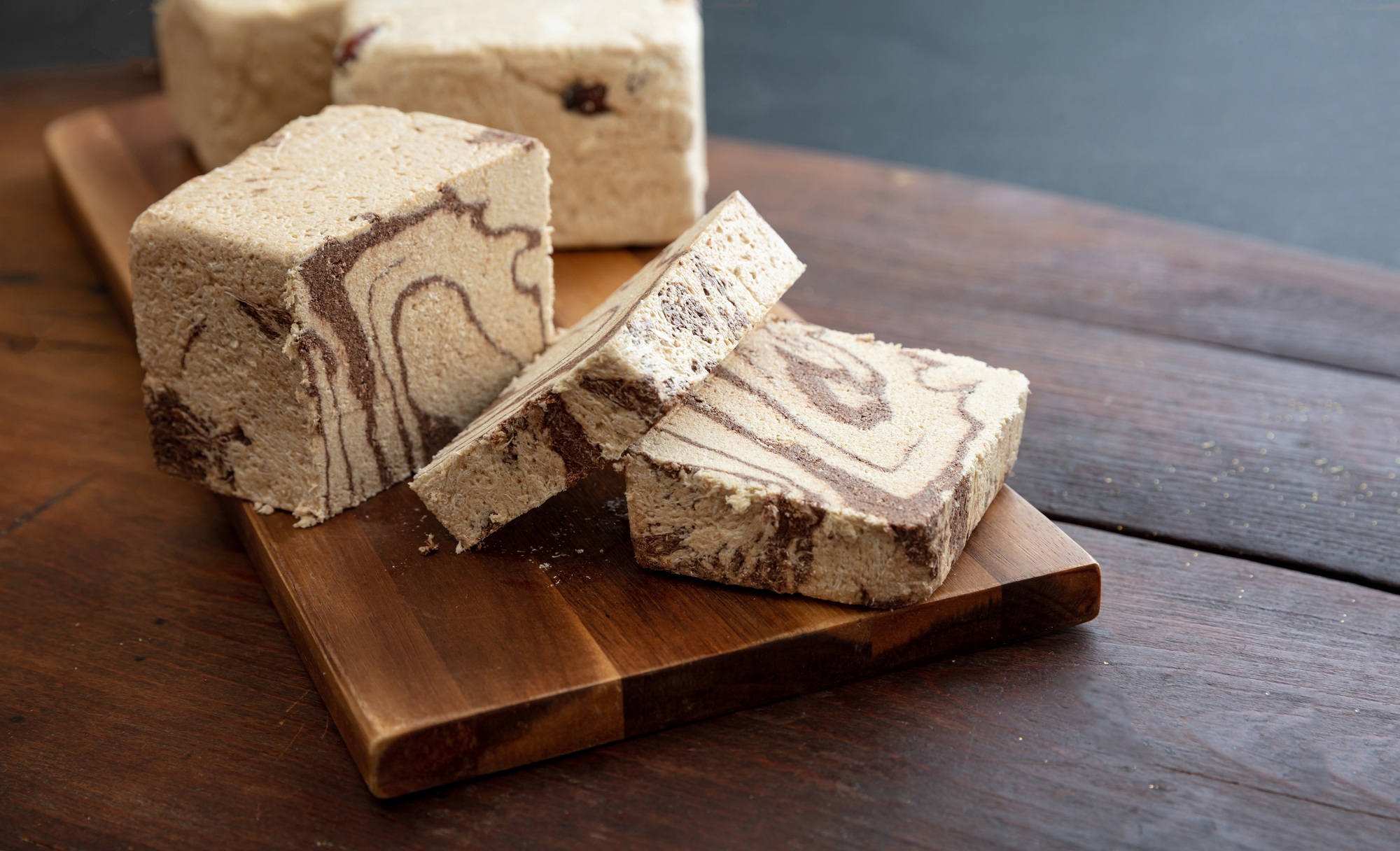 Halva cocoa slices on wooden table background, closeup view.